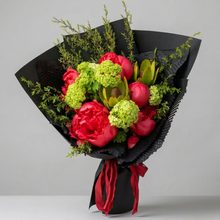 Load image into Gallery viewer, Red peonies with green seasonal flowers and foliage in black wrapping with red ribbon.